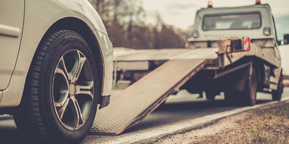 Loading broken car on a tow truck on a roadside