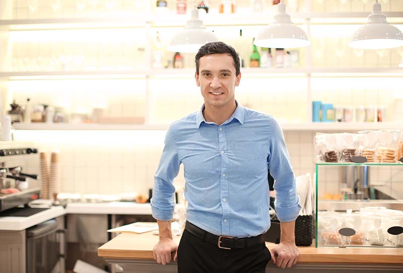 Young man standing in store. Small business owner portrait.